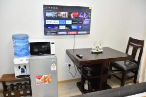 Zimmer mit einem Tisch, einem Kühlschrank und einem TV in der Unterkunft Sky Studio in Nairobi