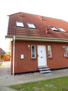 ein rotes Backsteinhaus mit einer weißen Tür in der Unterkunft Charmantes lütt Eckhus Zingst in Zingst