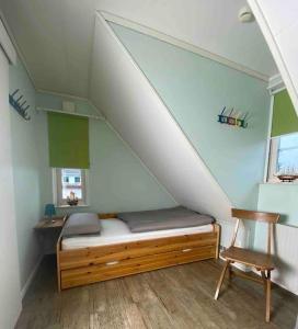 a small bedroom with a bed and a chair at Charmantes lütt Eckhus Zingst in Zingst