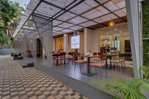 De Garland Palolem - AM Hotel Kollection في بالوليم: مطعم بطاولات وكراسي في مبنى