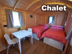 Habitación pequeña con 2 camas y mesa. en Camping Melezza en Losone