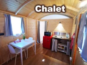 eine kleine Küche mit einem weißen Tisch und einem roten Kühlschrank in der Unterkunft Camping Melezza in Losone
