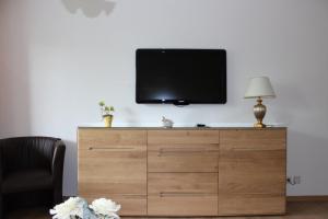 einen Flachbild-TV auf einer Holzkommode in der Unterkunft Ferienwohnung Rosenstraße in Langenargen