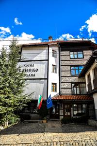 un bâtiment avec deux drapeaux devant lui dans l'établissement Family Hotel Bansko Sofia, à Sofia
