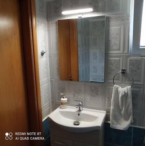 a bathroom with a white sink and a mirror at View-Family Apartment in Moúdhros +14 photos