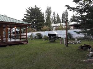 een achtertuin met een paviljoen en een grill in het gras bij Cabaña Familiar El Refugio in Potrerillos