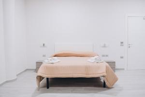 Una cama en una habitación blanca con dos toallas. en Prestige, en Trevico