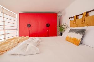 1 dormitorio con cama blanca y puerta roja en Sea Breeze Loft, en Livorno