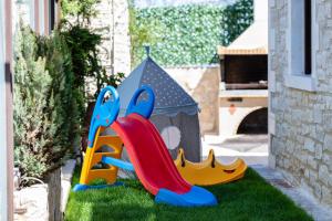a childrens playground with a slide on the grass at Sokaki Villas, rustic ambience, By ThinkVilla in Khromonastírion