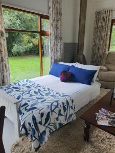 a bedroom with a bed with blue and white sheets and a window at Beautiful garden cottage in Stormsrivier