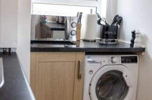 a kitchen with a microwave and a washing machine at Luxury 3 bedroomed home in Kettering