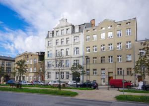 a large white building with cars parked in a parking lot at Studio Bueno 5.2 - ACCO RENT in Gdańsk