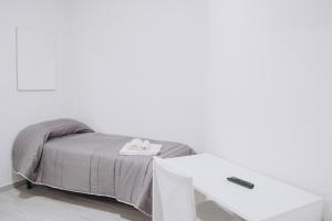 a bed with a white table next to a white wall at Prestige in Trevico