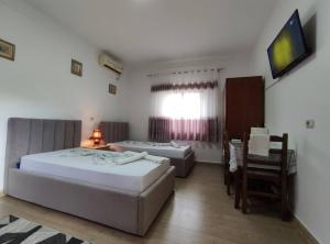 um quarto com 2 camas, uma mesa e uma televisão em Dona's Studio Apartment em Gjirokastër