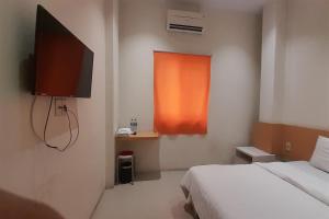a bedroom with a bed and a television and a window at SPOT ON 92481 Modena Homestay Syariah in Medan
