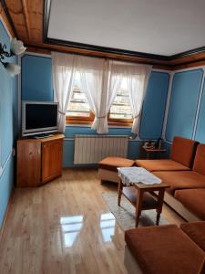 un salon avec un canapé et une télévision dans l'établissement Астра къща за гости, à Koprivchtitsa