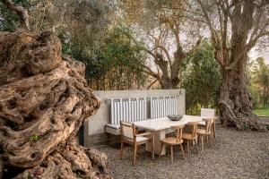 a table and chairs and a bench and trees at Villa 7 in Perivólia