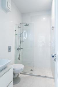La salle de bains blanche est pourvue d'une douche et de toilettes. dans l'établissement Vitosha Str 2BD White & Blue Apt, à Sofia