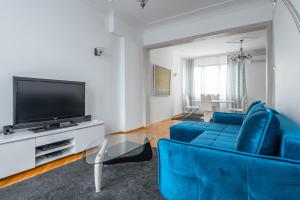 a living room with a blue couch and a tv at Vitosha Str 2BD White & Blue Apt in Sofia