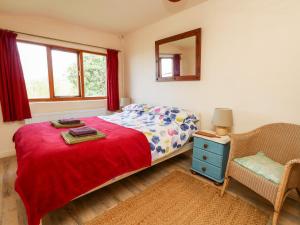 1 dormitorio con cama, silla y espejo en Eweleaze en Dorchester