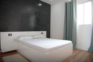 Una cama blanca en una habitación con ventana. en Duarte Apartments - Vista, en Mindelo 4 fotos más
