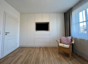 Dieses weiße Zimmer verfügt über einen Stuhl und einen TV. in der Unterkunft DünePur in Norderney