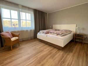 a bedroom with a bed and a chair and a window at DünePur in Norderney