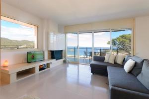 a living room with a couch and a tv and windows at Pool and sea views apartment with 1 parking space in Tossa de Mar