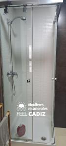 La salle de bains est pourvue d'une douche avec une porte en verre. dans l'établissement Apartamento Calderón, Feel Cádiz, à Cadix