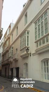 un bâtiment blanc avec un panneau sur son côté dans l'établissement Apartamento Calderón, Feel Cádiz, à Cadix