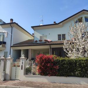 una casa blanca con una puerta y árboles en flor en La Casa Nel Gelso, en Bellaria-Igea Marina