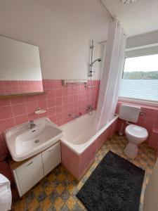 een roze badkamer met een wastafel, een bad en een toilet bij Ferienwohnung Hinterberg in Fürstenstein