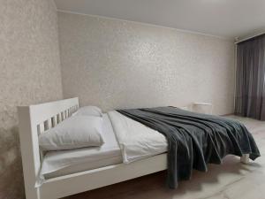 a bedroom with a white bed with a black blanket at Апартаменти Молоді LutskDoba in Lutsk