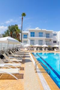a pool with chairs and umbrellas next to a building at Mia Hotel Apartment in Ayia Napa