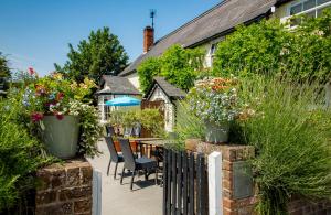 a patio with a table and chairs and flowers at The Cricketers Clavering in Clavering