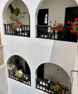 a building with three archways with flowers on them at Riad Dar Awil in Essaouira +101 photos