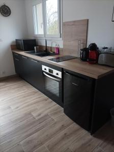 a kitchen with black cabinets and a wooden counter top at Loft sauna jacuzzi ospariegeois in Lavelanet