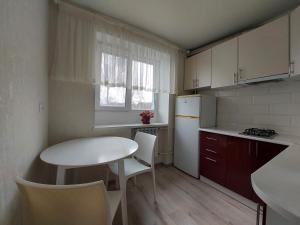 Апартаменти Молоді LutskDoba في لوتسك: مطبخ صغير مع طاولة وثلاجة بيضاء
