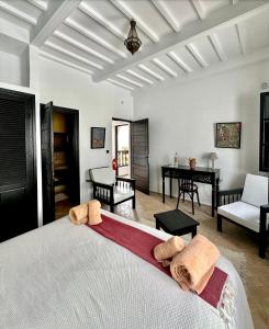 a bedroom with a large white bed and a desk at Riad Dar Awil in Essaouira