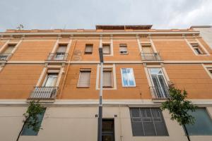 een hoog oranje gebouw met ramen en een straatbord bij Two bedroom flat in PobleNou in Barcelona