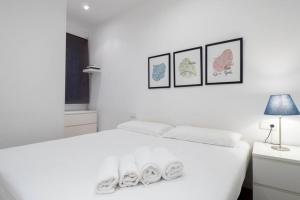 een witte slaapkamer met een wit bed met drie foto's aan de muur bij Two bedroom flat in PobleNou in Barcelona