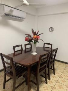 a wooden table with chairs and a vase with flowers on it at Modern with class near Airport in Nadi