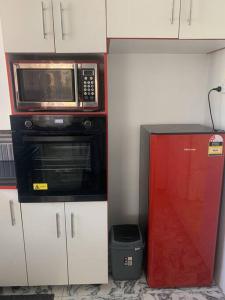 a kitchen with a microwave and a red door at Modern with class near Airport in Nadi