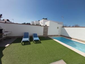 two chairs sitting on a lawn next to a swimming pool at Casa Los Naranjos 3 in Cádiz