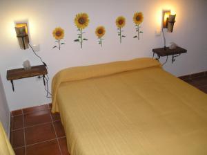 1 dormitorio con 1 cama con girasoles en la pared en Casa Rural La Posada Del Frances, en Villarrubia de Santiago