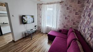 ein Wohnzimmer mit einem lila Sofa vor einem Fenster in der Unterkunft Sakņu 16/18 in Daugavpils