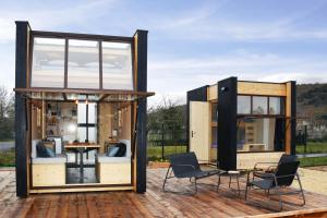 two shipping container homes with chairs and a table at LE 12 in Ébreuil