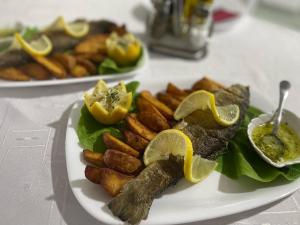 une assiette de nourriture à base de poisson, de pommes de terre et de tranches de citron dans l'établissement Apartmani Joja, à Kuršumlija