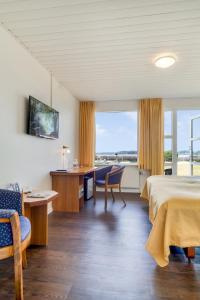 Habitación de hotel con cama, escritorio y sillas en Hotel Pinenhus en Glyngøre