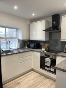 a kitchen with white cabinets and a stove top oven at Abacus House - TWO Bedroom Apartment in Huntingdon